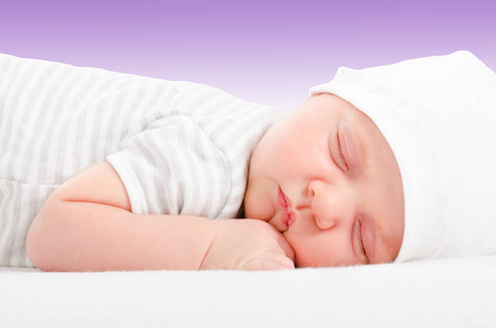 一个可爱的新生儿的肖像在紫色背景的睡眠婴儿