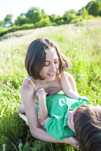 男孩和他的母亲躺在草地上。一个女人和她的儿子在夕阳下的田野里散步。这孩子和妈妈在大自然里共度时光。妈妈的微笑。孩子在拥抱母亲