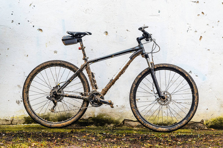 肮脏的山地自行车骑在恶劣的天气站后, 布满了泥土。灰色 29er Hardtail 自行车在白色墙壁背景