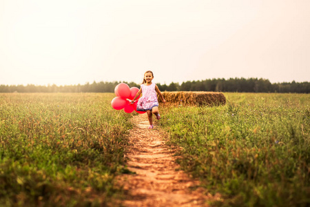 女孩在自然界中与红色气球一起奔跑