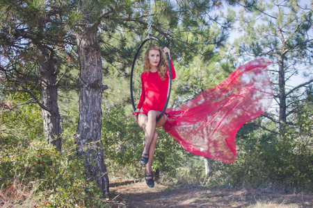 适合妇女在瘦瘦的衣服跳舞与空中丝绸在森林背景下, 在空中丝绸体操运动员训练
