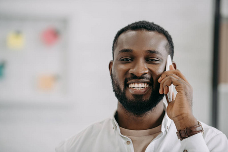微笑英俊的非洲裔美国商人的肖像在办公室智能手机交谈