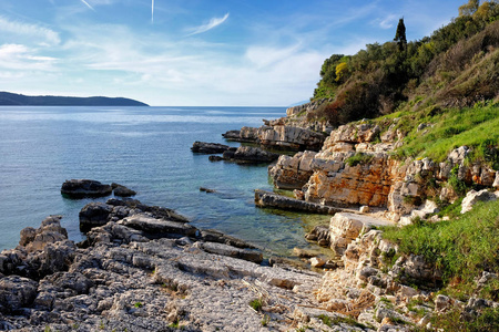 在 Kassiopi 的岩石 Bataria 海滩与在科孚, 希腊