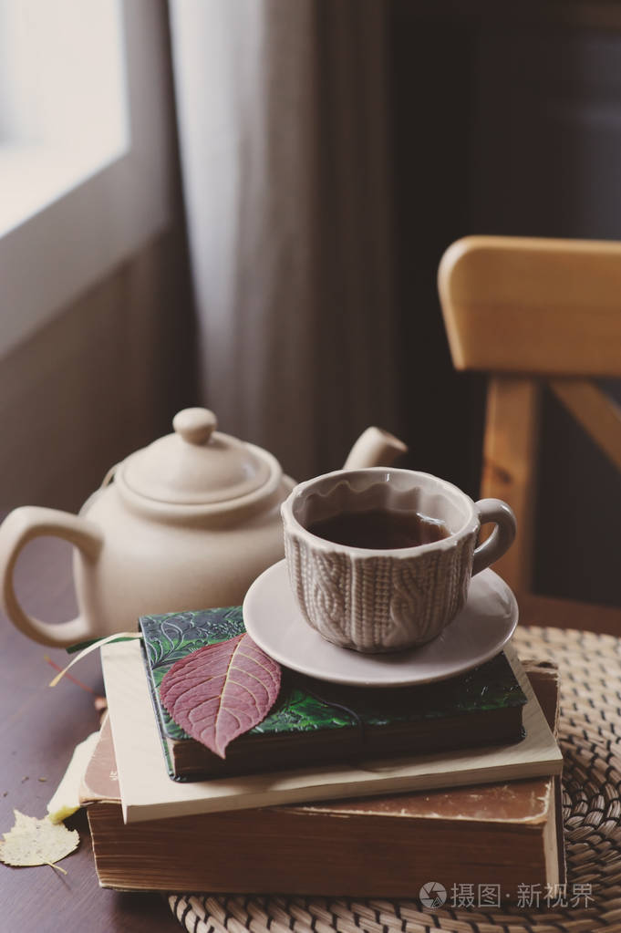 舒适的秋天早晨在乡下房子, 杯子茶和书在木桌.静物资料