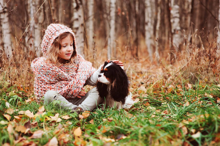 快乐的孩子女孩玩她的骑士国王查尔斯猎犬狗在秋季, 在阳光明媚的花园或森林散步户外