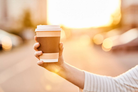女孩在日落时拿着一杯咖啡
