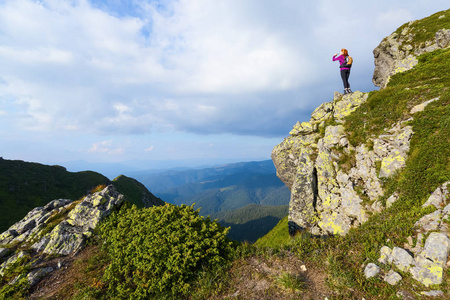 运动型的背袋是站在悬崖边，观看上无尽广阔的山脉景观在阳光灿烂的日子