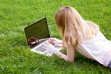 女孩在草坪上打字笔记本电脑