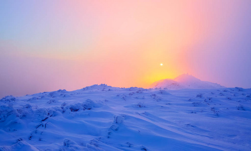 日出照亮天空，山和树站在雪堆被冻雪与黄色光芒覆盖