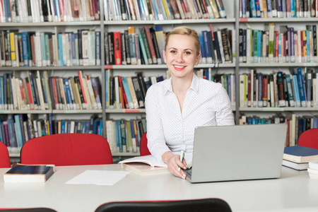 学生准备考试和学习课在学校图书馆图书馆中的笔记本电脑与浏览互联网的研究