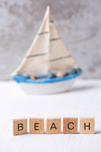 字海滩从木块和小船玩具反对灰色墙壁