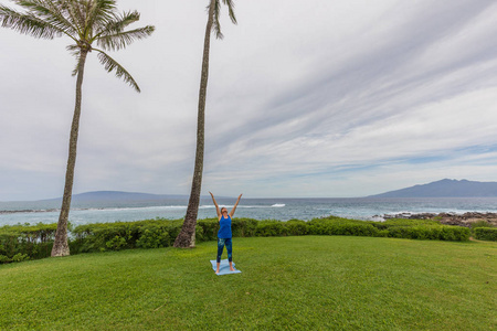 在毛伊岛夏威夷风景秀丽的海岸上练习瑜伽的妇女