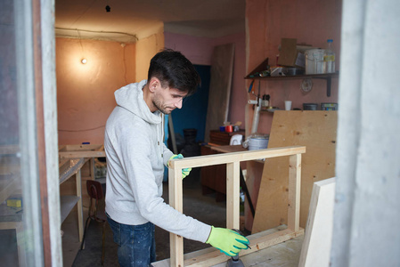 在公寓修理的年轻人与木头一起工作