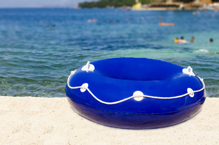 一个蓝色的橡胶环 浮标 躺在沙滩上, 蓝色的大海, 和蓝色的天空在夏天, 旅行的概念