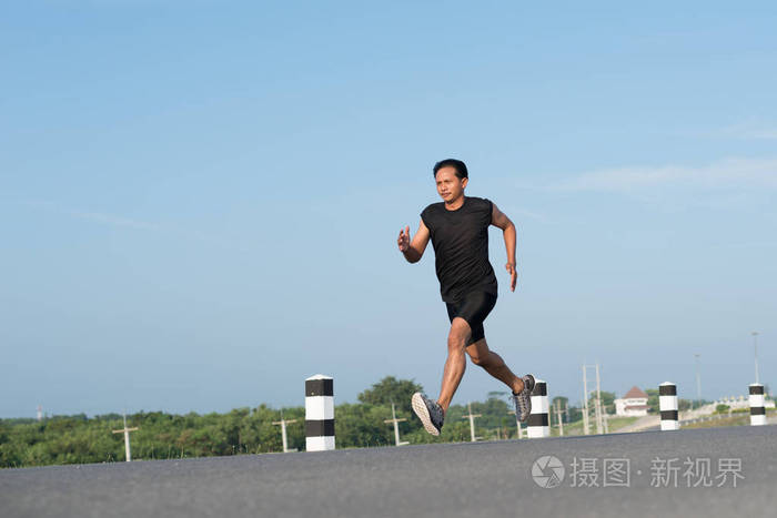 亚洲年轻人奔跑在时间在日出期间在水坝路锻炼.健康的