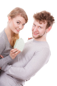 住房家庭未来抵押贷款财政概念。性格开朗的年轻夫妇的房子模型。年轻的男人和女人微笑带回家的符号