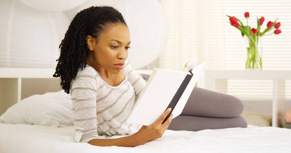 在床上阅读的黑人妇女