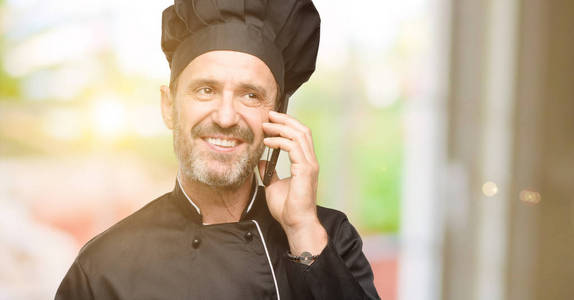 高级厨师, 戴着厨师帽高兴地用智能手机交谈