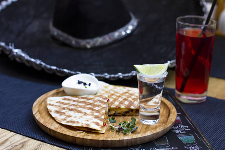 杯龙舌兰酒与石灰和部分 quesadilla 在圆木板与草帽背景, 墨西哥菜, 选择性重点