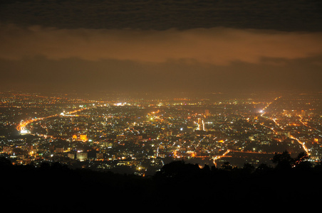 查看在晚上用灯和城市泰国为背景