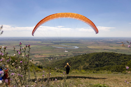 一个人从托卡伊山上带着橙色降落伞起飞