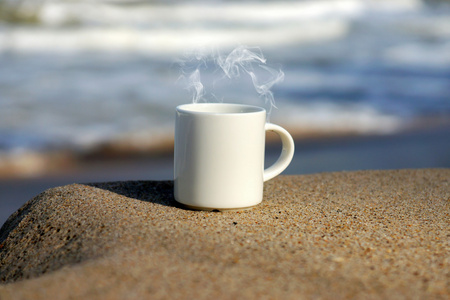 在海滩上的白色咖啡杯