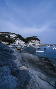 当地的渔船和小岛的岩石海岸视图
