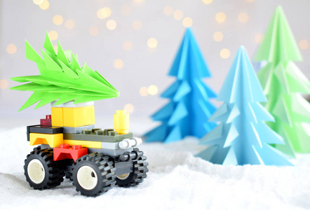 折纸3d 圣诞树从纸在白色背景, bokeh 灯和玩具汽车。圣诞快乐, 新年贺卡。纸艺风格。复制空间。选择性对焦
