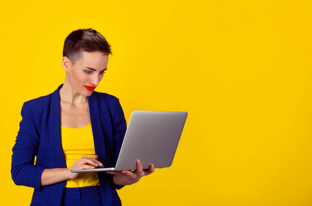 图片的可爱的女人工作在电脑笔记本电脑上孤立的黄色背景站在副本空间的左侧