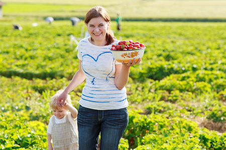 母亲和她小的孩子孩子有机草莓农场