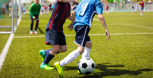 初中足球比赛比赛。两个年轻的足球运动员赛跑和争夺球。青年足球锦标赛
