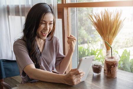 快乐的女人在咖啡馆里使用平板电脑