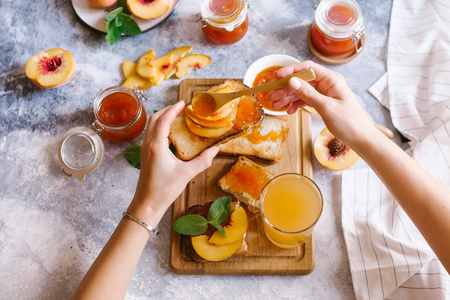 用杏果酱和新鲜水果和白色木桌上的树叶敬酒。美味早餐