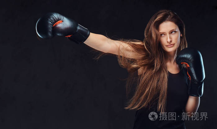 照片 美丽的黑发女拳击手在拳击练习中 专注于一个严重的面部集中的