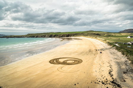 在多内加尔爱尔兰白色沙滩的图片与最近轮胎胎面标记, 形成圈子在沙子