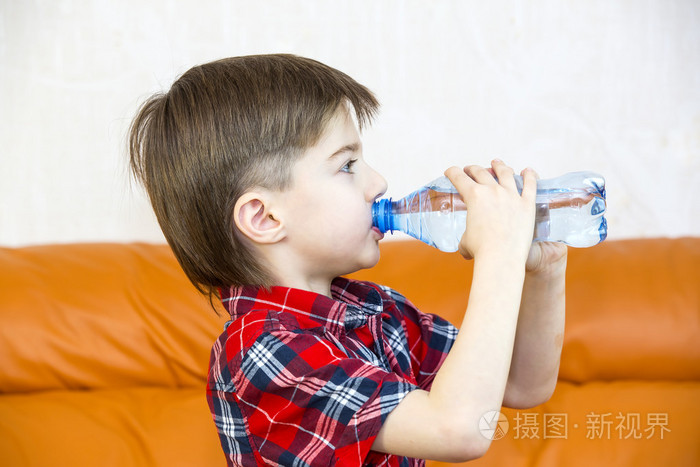 男孩从一个塑料瓶喝水