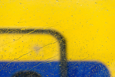 玻璃上的雨滴和蓝色和黄色的背景