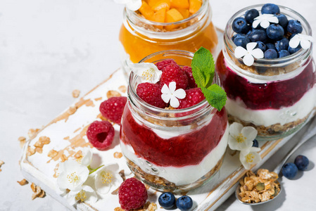 甜点与麦片, 莓果和果子泥在罐子在白色桌, 上部看法水平