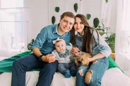 幸福家庭的水平肖像坐在床上抱着宝宝和兔子