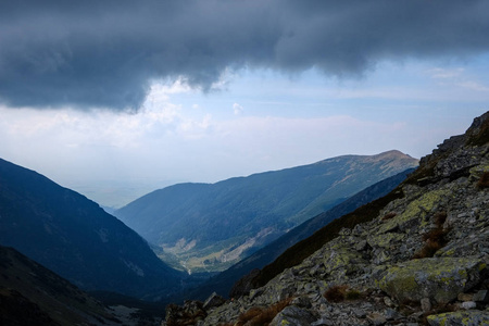 从斯洛伐克的 Banikov 山顶的山脉全景塔特拉山脉与岩石景观和远足者的阴影在明亮的天与风暴云接近在阴天