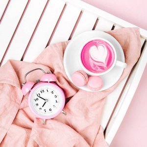 白色木质托盘上有钟表和粉红色布料的咖啡杯