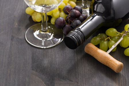 瓶的红葡萄酒和葡萄在木制的背景，特写