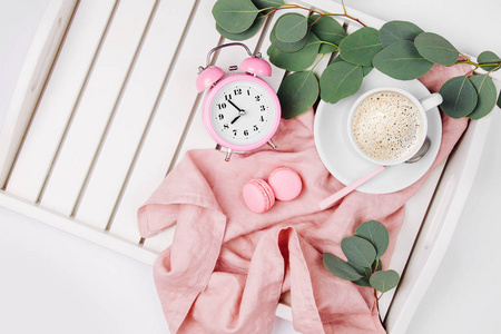 杯咖啡与马卡龙, 时钟和桉树树枝上服务托盘粉红色织物
