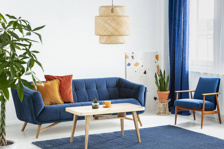 扶手椅和沙发, 在蓝色和橙色的客厅内部与灯以上的木桌。真实照片