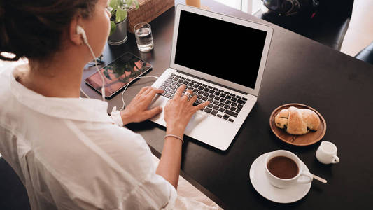 年轻的妇女学生与笔记本电脑坐在咖啡厅和工作与笔记本电脑