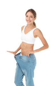 年轻苗条妇女在老大牛仔裤显示她的饮食结果在白色背景