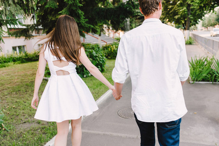 一对漂亮的情侣一起走在公园里手持和挥舞着他们的手