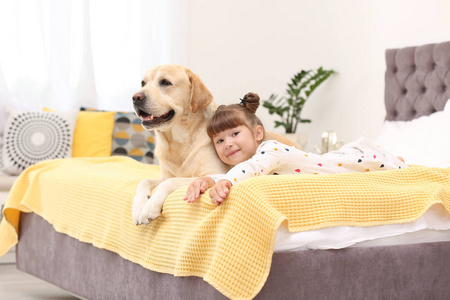 可爱的黄色拉布拉多猎犬和小女孩在床上在家