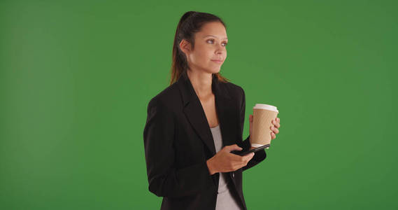 沉思的女性企业专业与咖啡使用手机在绿色屏幕上