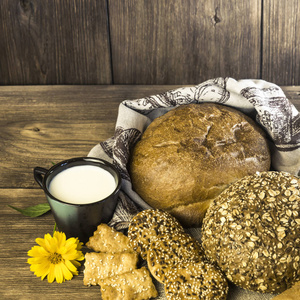 食品。质朴的静物。在面包店, 饼干和一杯牛奶在木桌背景下烘烤的新鲜面包的种类